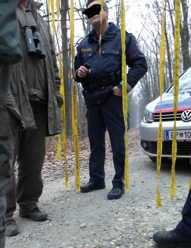 Polizist steht vor seinem Einsatzfahrzeug und spricht mit Jägern
